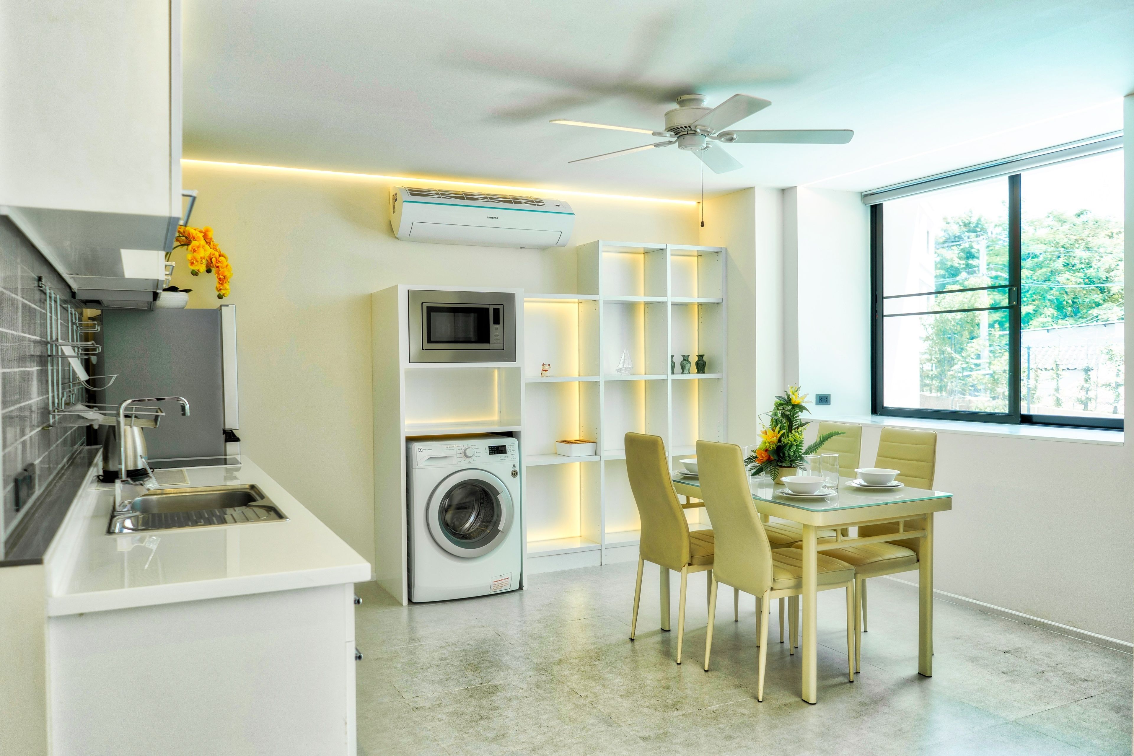 Una cocina moderna con lavadora integrada, una zona de comedor con mesa y sillas, y un ventanal con vistas.