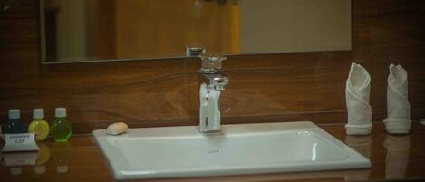 A bathroom with a white sink, a mirror, and a wooden vanity. There are toiletries on the counter.