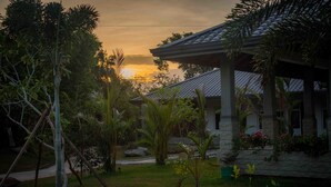 A house with a tiled roof, surrounded by a garden with various plants and a pathway. - Sungreen Resort (Habarana)