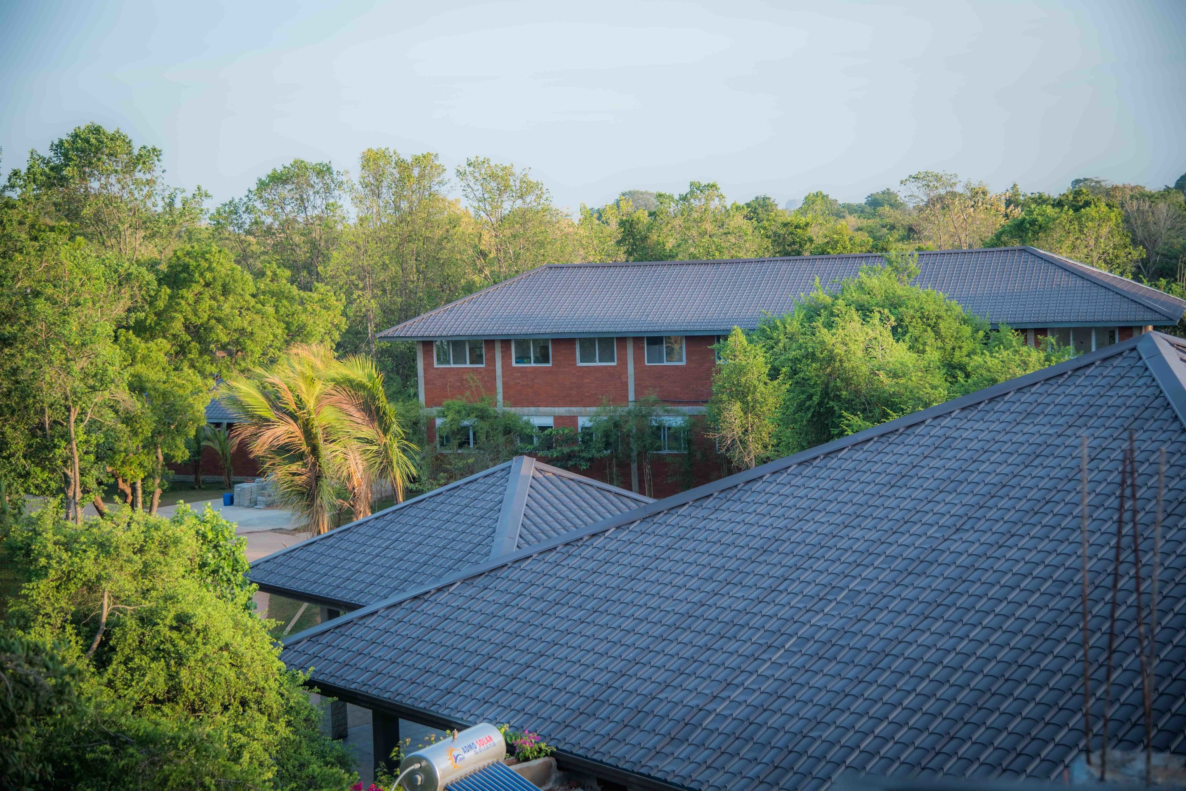 A residential area with multiple houses, each with a tiled roof and surrounded by lush greenery.