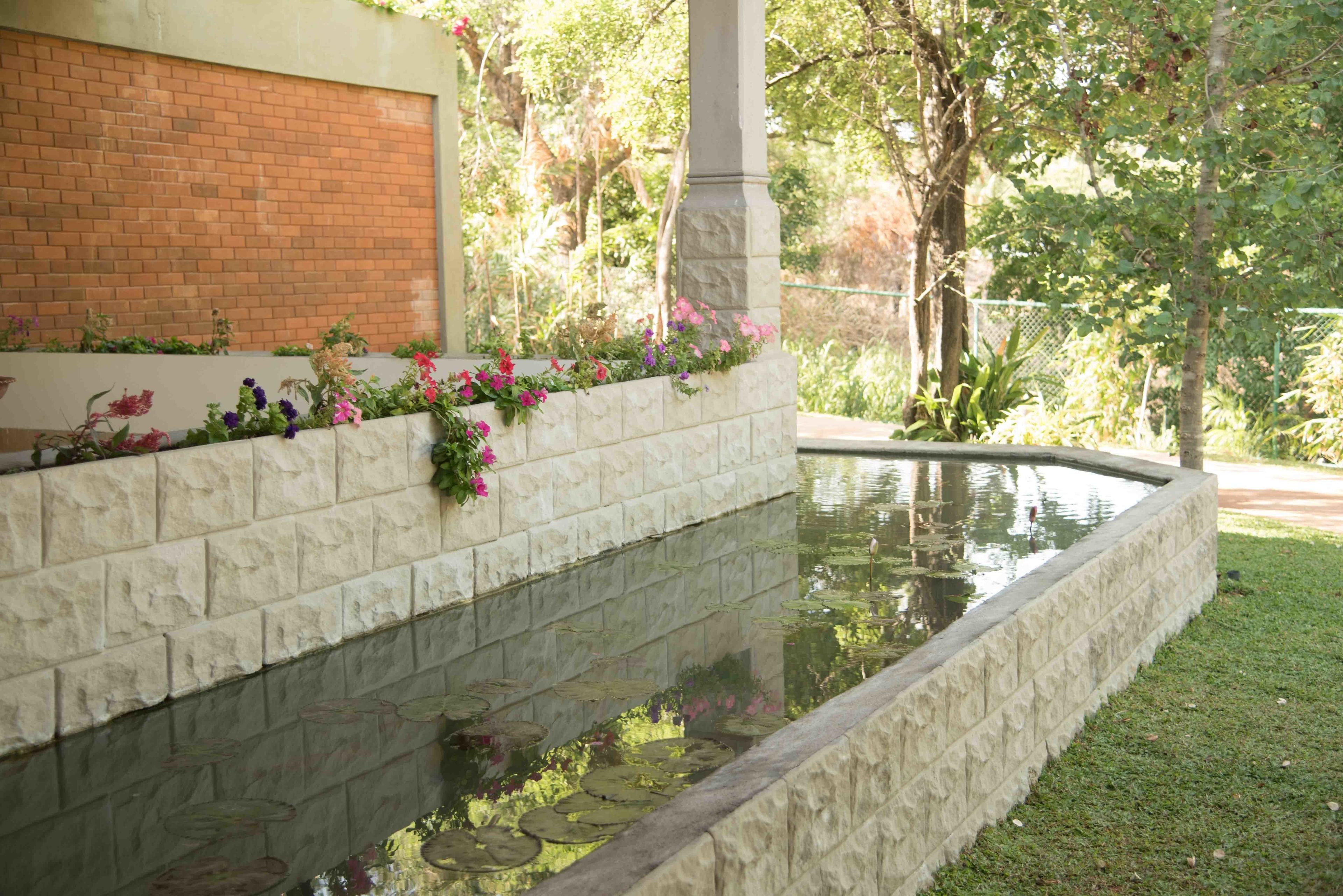 A garden with a pond, stone walls, and a brick wall.