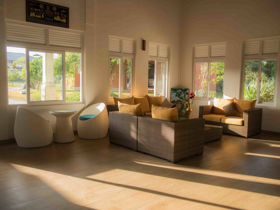 Amplia sala de estar con un conjunto de sofá moderno, una mesa de centro redonda y un asiento individual original. Ventanas grandes permiten que la luz natural inunde la habitación.