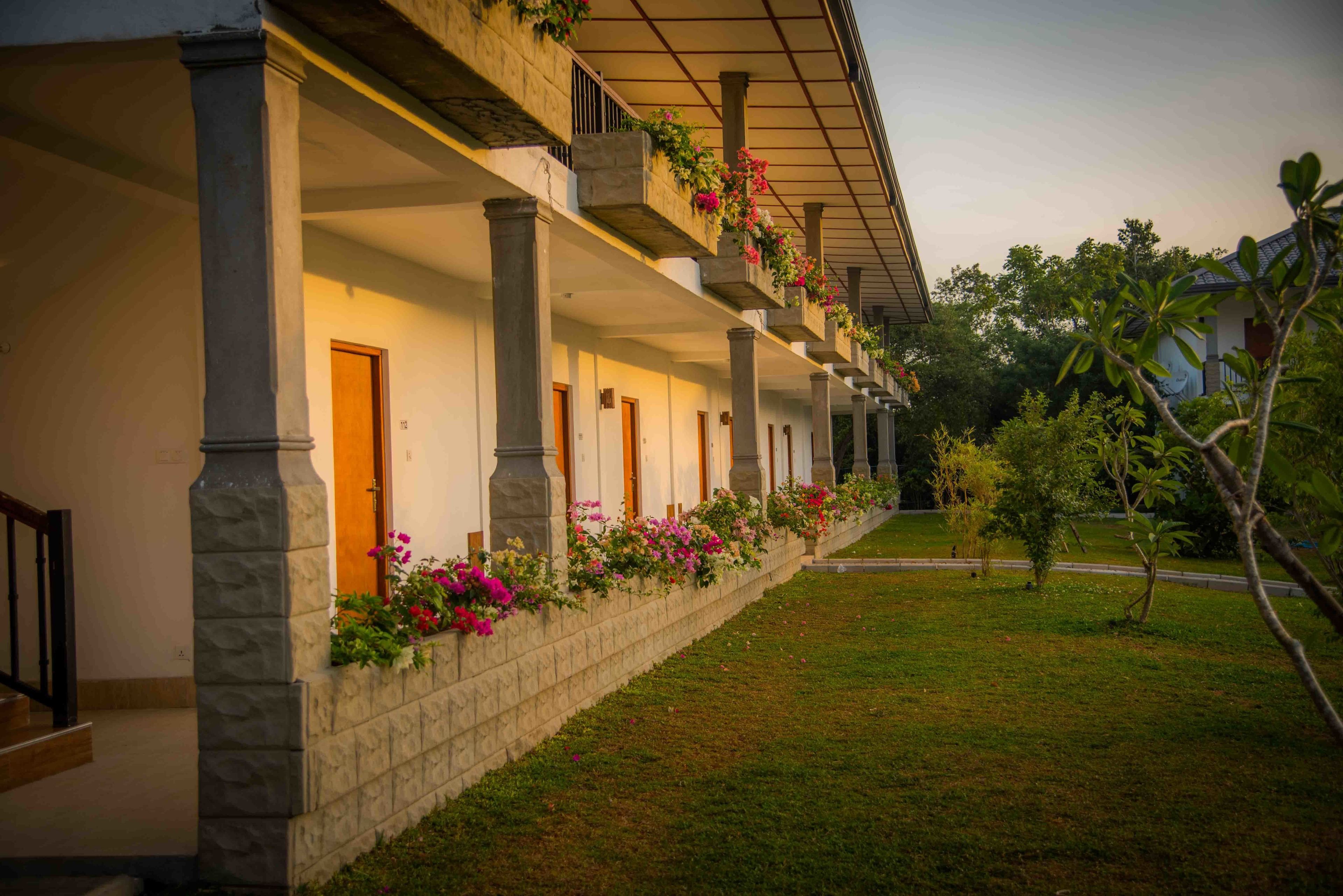A hotel with a covered outdoor area, stone columns, and flower boxes on the balconies.