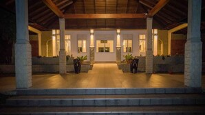A covered entrance with stone columns, a tiled floor, and potted plants. - Sungreen Resort (Habarana)