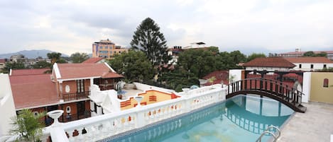 A rooftop pool with a decorative railing, surrounded by buildings and trees.