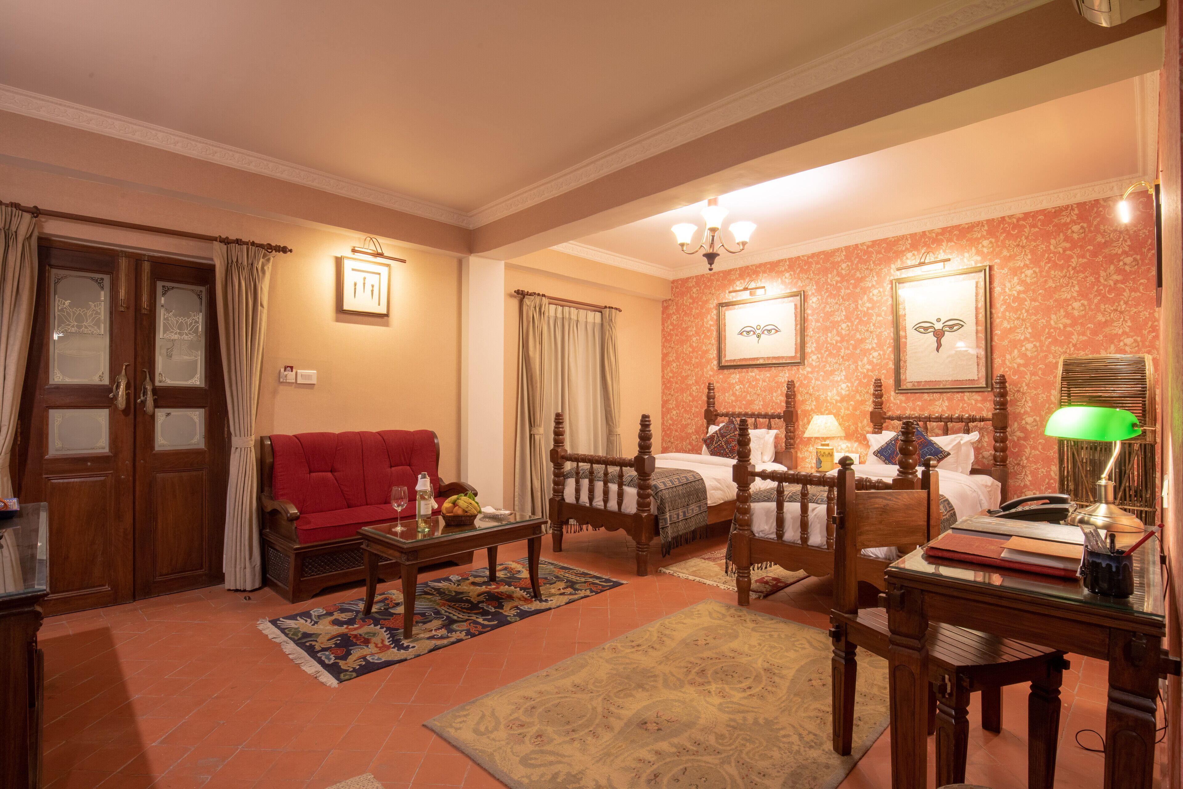A cozy room with a wooden bed, a red sofa, a wooden table, and a patterned rug.