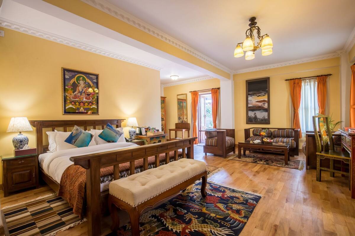 Una habitación de hotel con una cama, un banco, un sofá y una mesa de comedor.