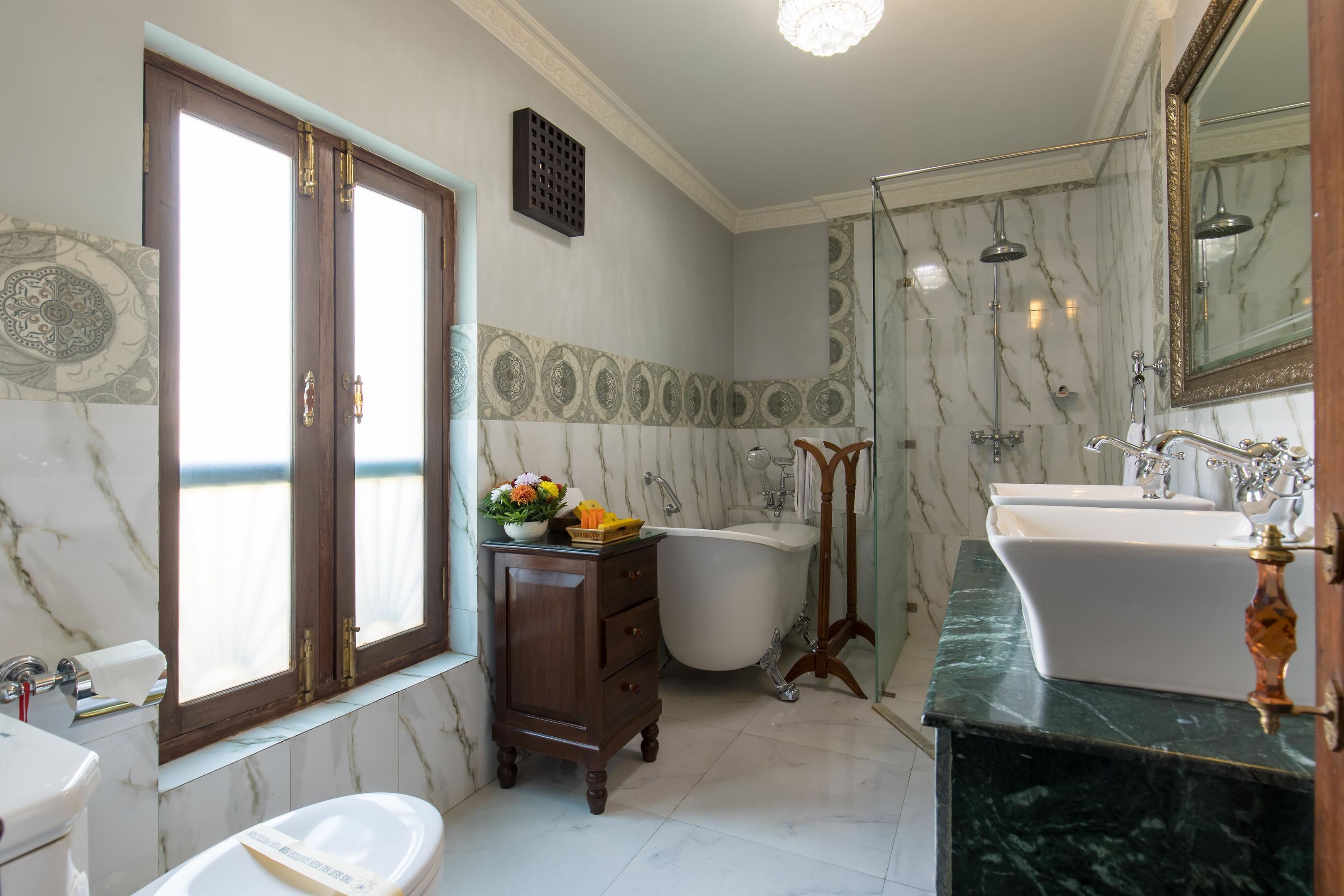 A bathroom with a bathtub, two sinks, a vanity, and a large mirror.