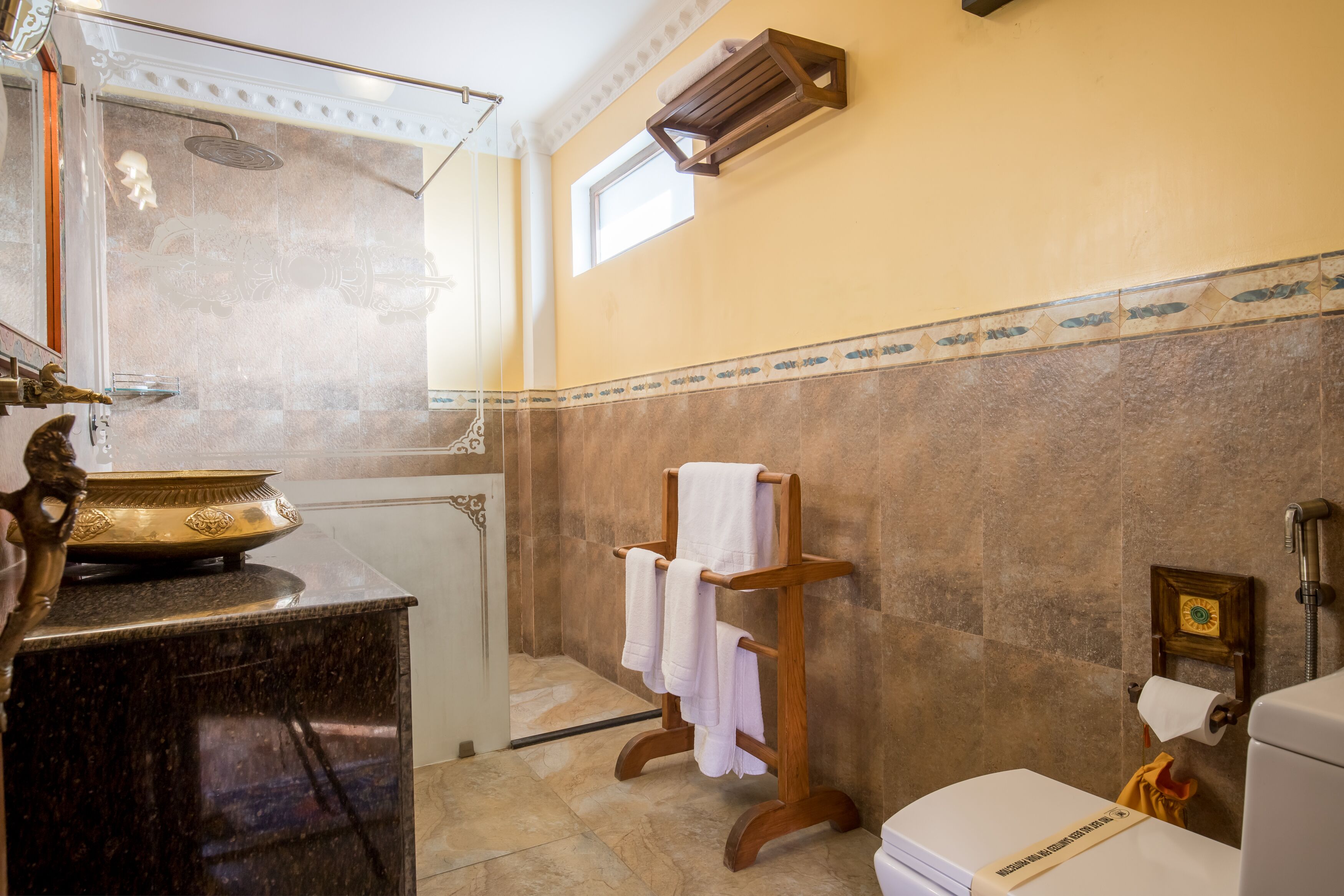 A bathroom with a marble vanity, a wooden towel rack, a toilet, and a shower area.