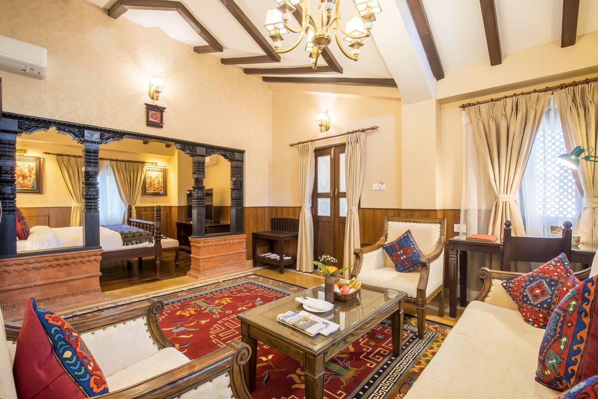 Una habitación tradicional con cama, sofá, mesa de centro y espejo.