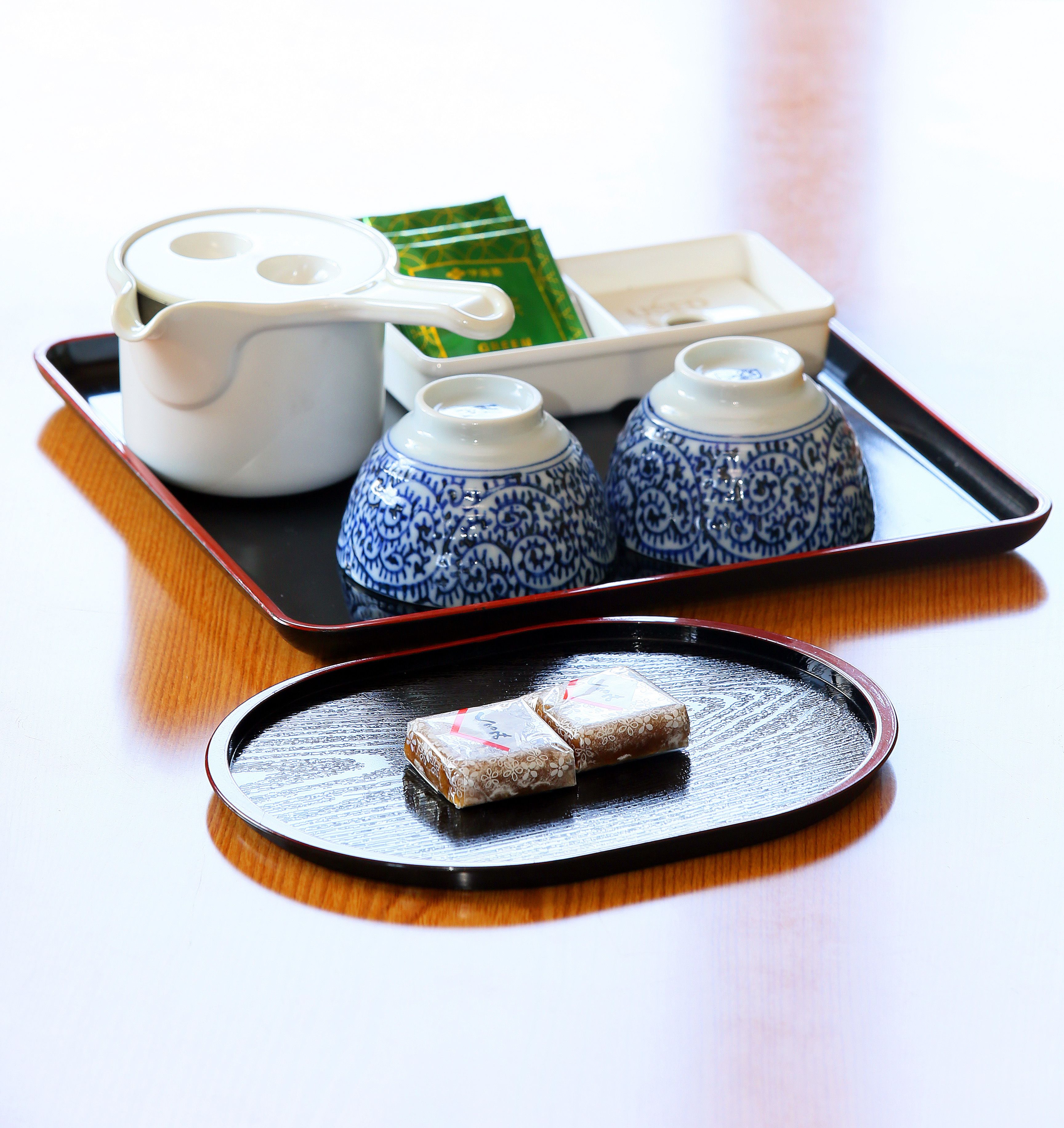 A tray with a teapot, two cups, a box of tea, and a plate with a wrapped item.