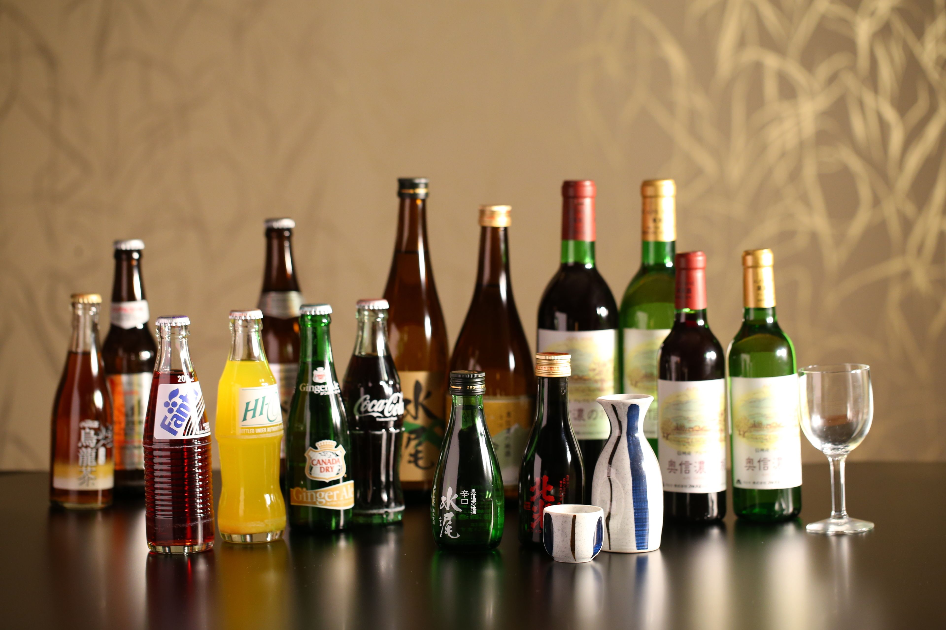 A variety of bottles and a wine glass on a table.