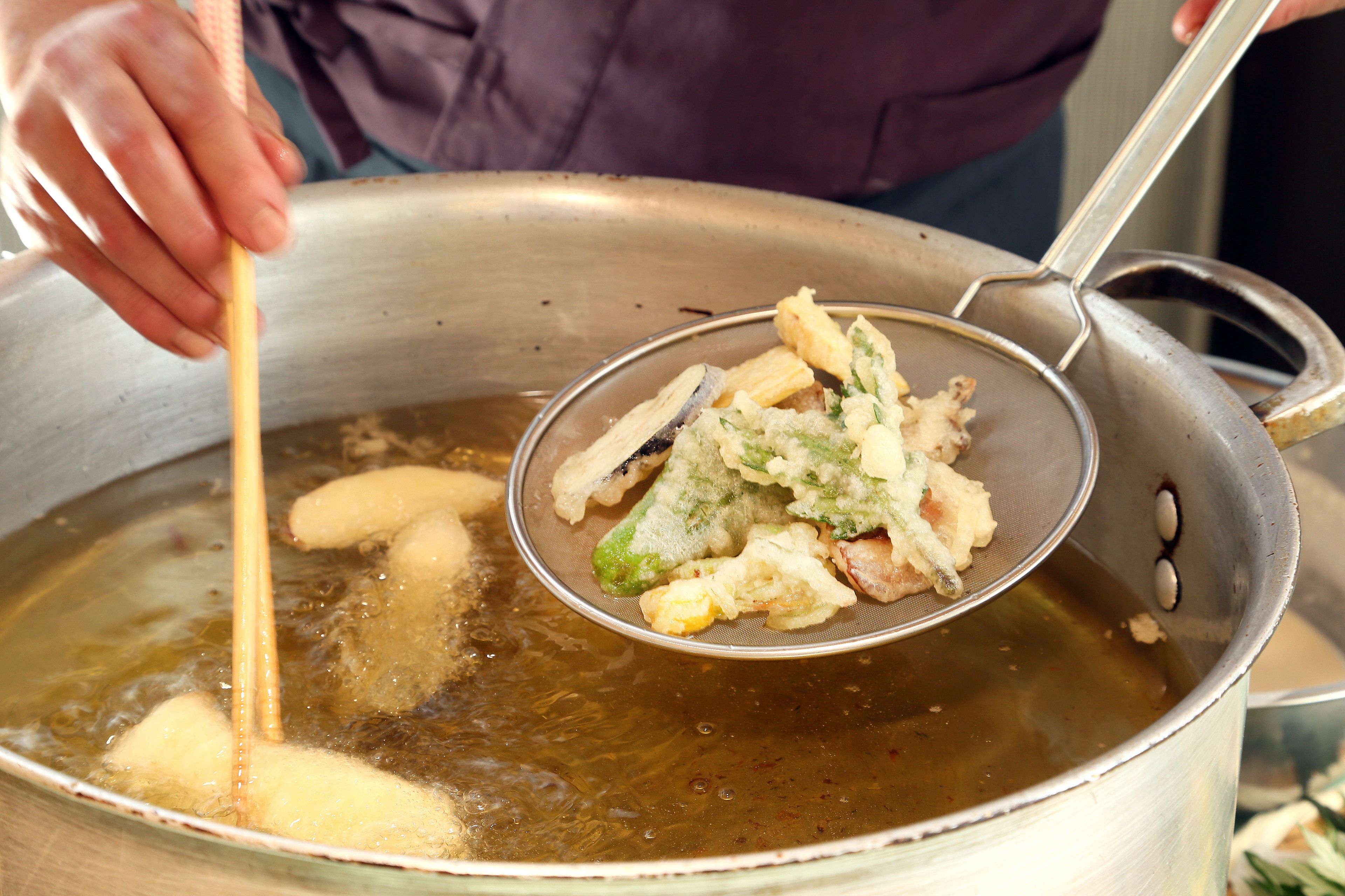 Une personne utilise une passoire pour retirer des aliments d’une casserole contenant un liquide bouillant.
