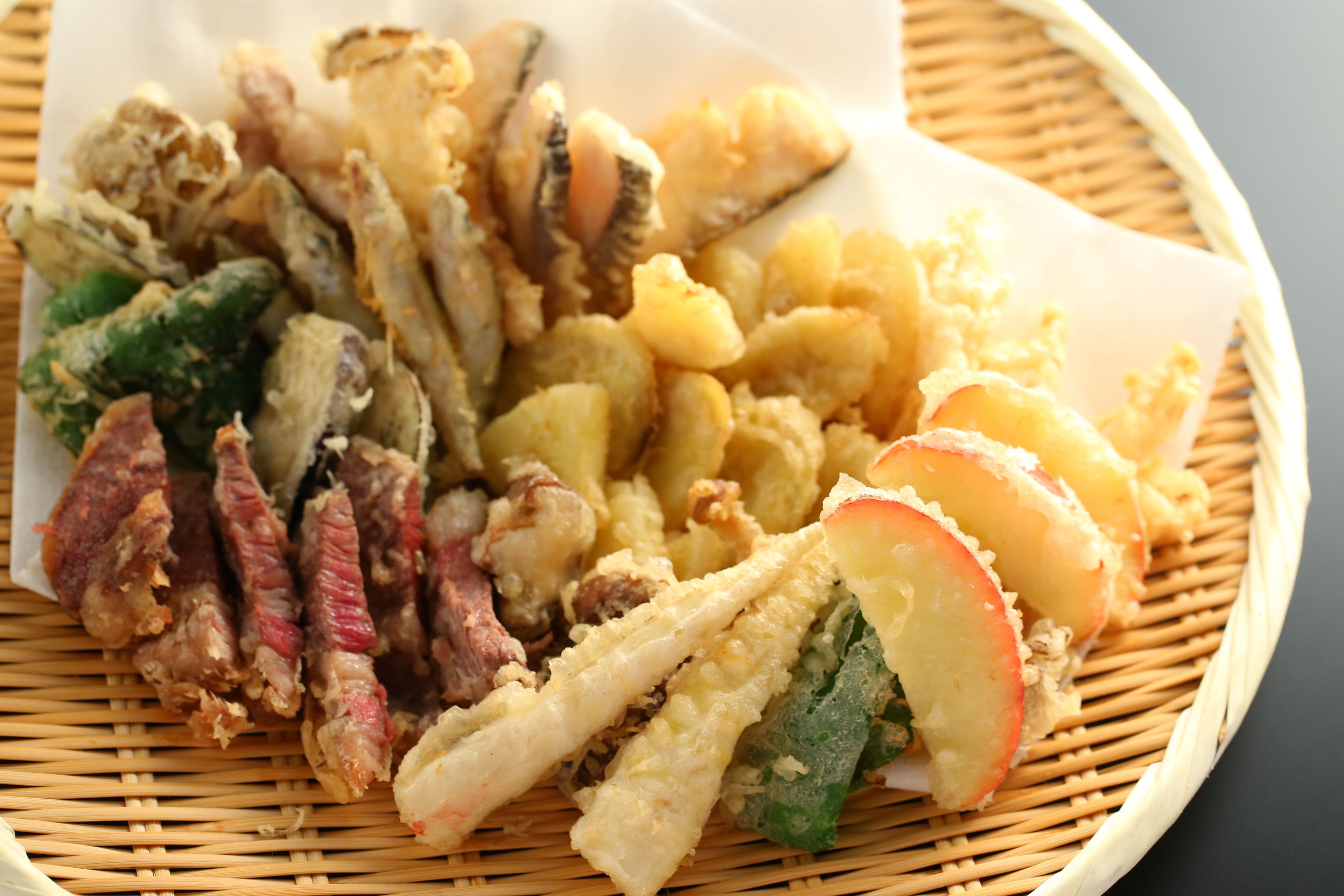 A basket containing various fried foods including tempura vegetables and shrimp.
