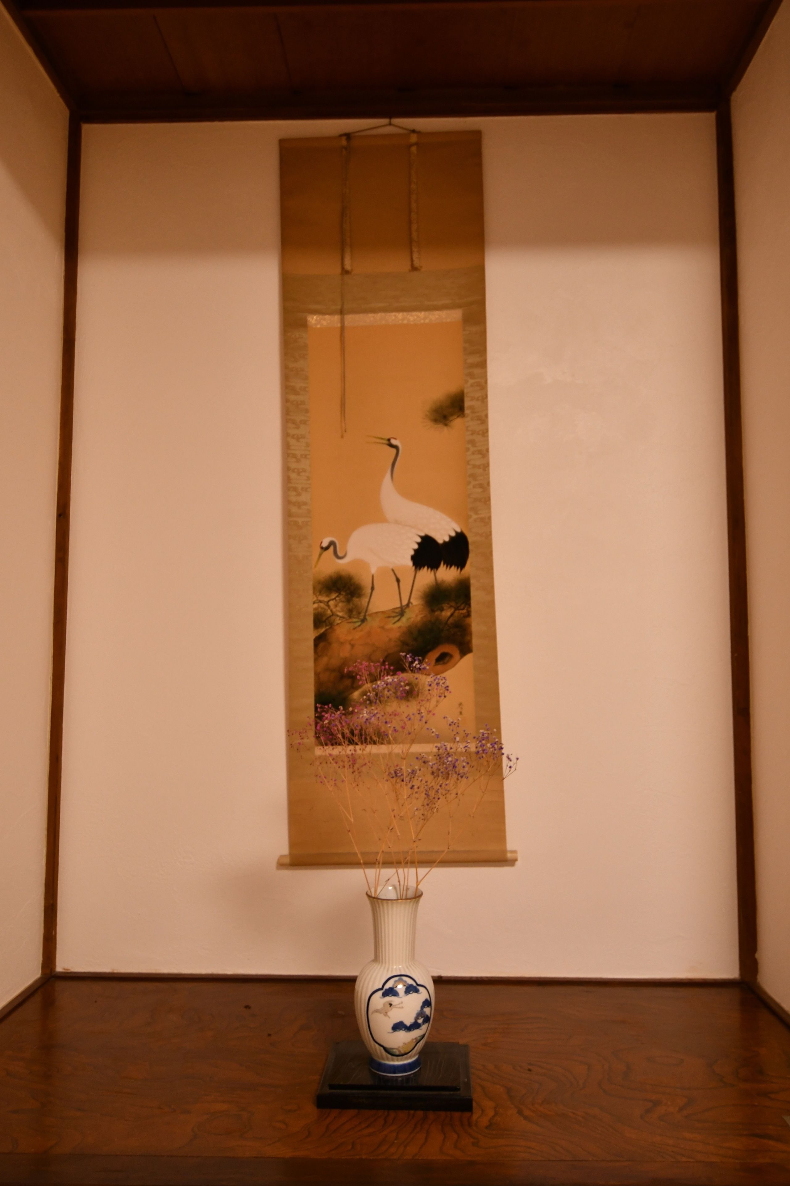 A framed artwork of a bird and flowers on a wooden floor.