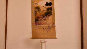 A framed artwork of a bird and flowers on a wooden floor.