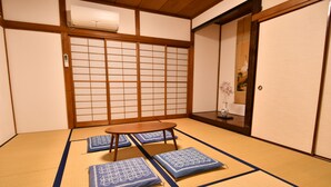 A tatami mat room with a low wooden table and cushions. - Hostel HANA AN (Tokyo)