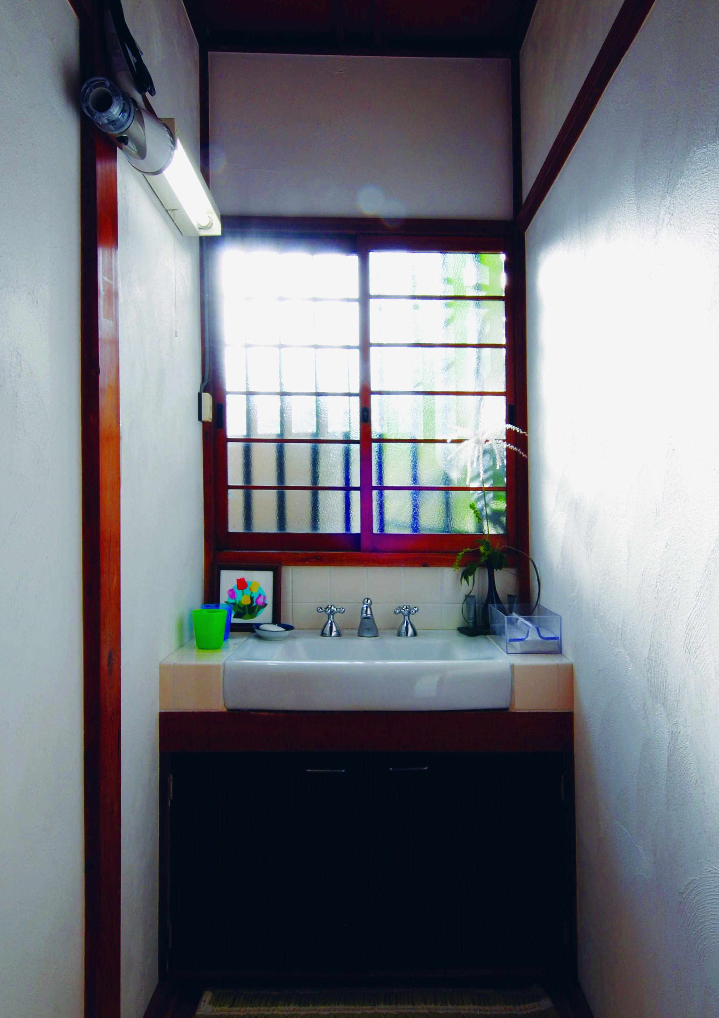 A bathroom with a window, a sink, and a mirror.