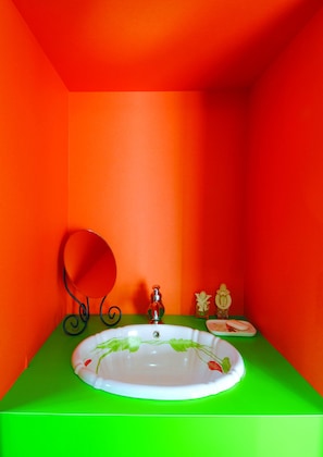 A bathroom with a white sink, green countertop, and orange walls. - Hostel HANA AN (Tokyo)