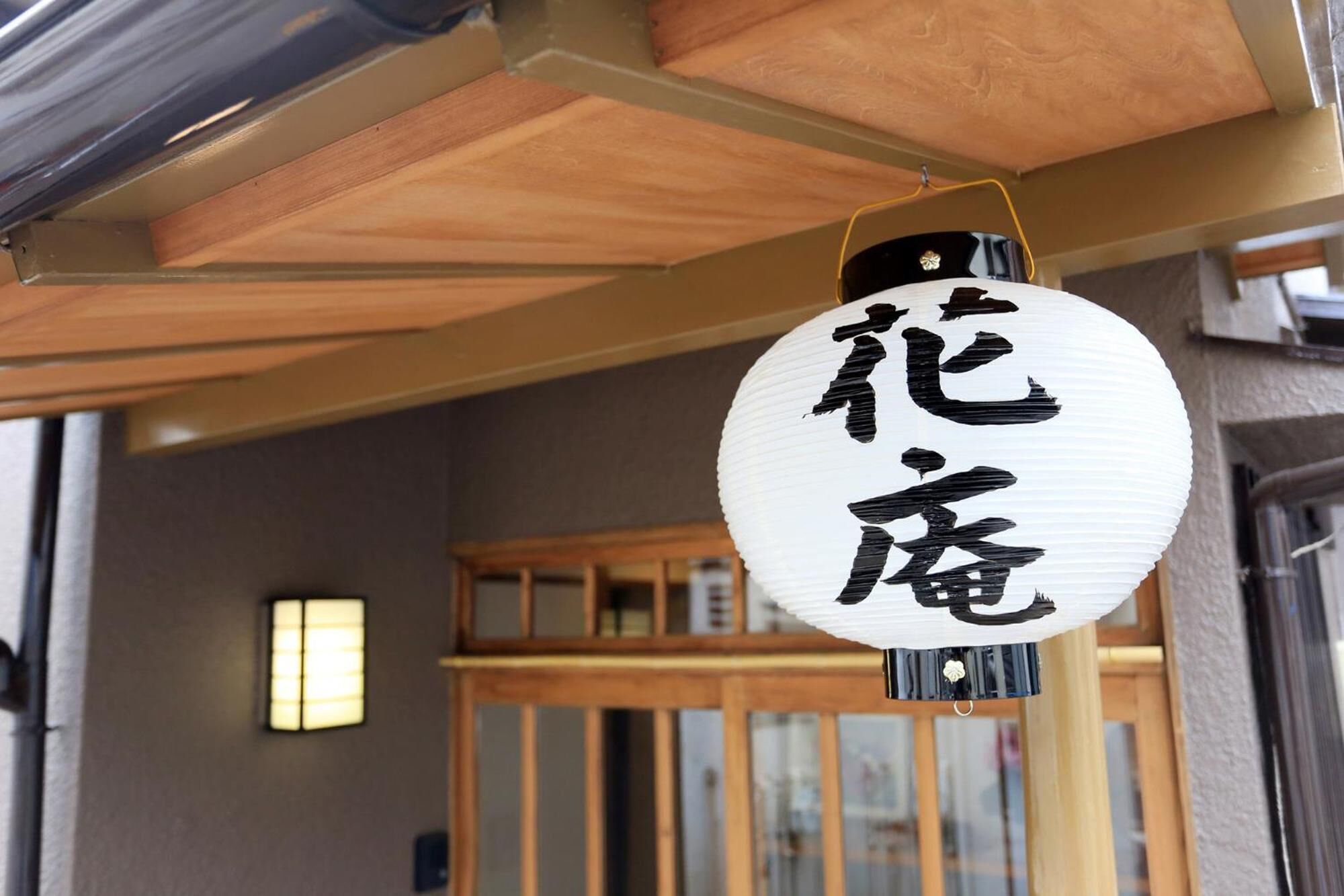 Een traditionele Japanse lantaarn met kalligrafie, hangend aan een houten balk.
