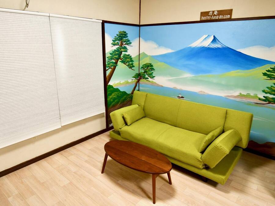 A room with a green sofa, a wooden coffee table, and a large wall mural depicting a mountain landscape.