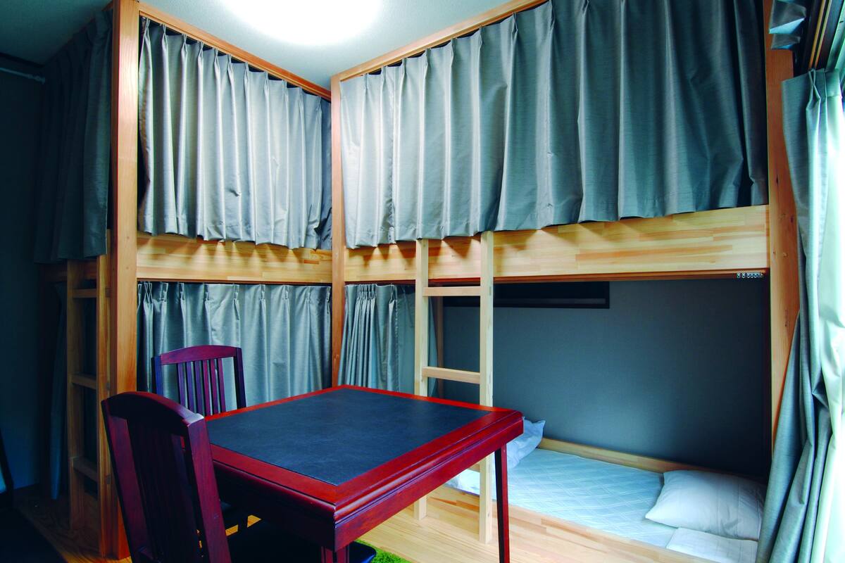 A dormitory room with bunk beds, a desk, and a chair.