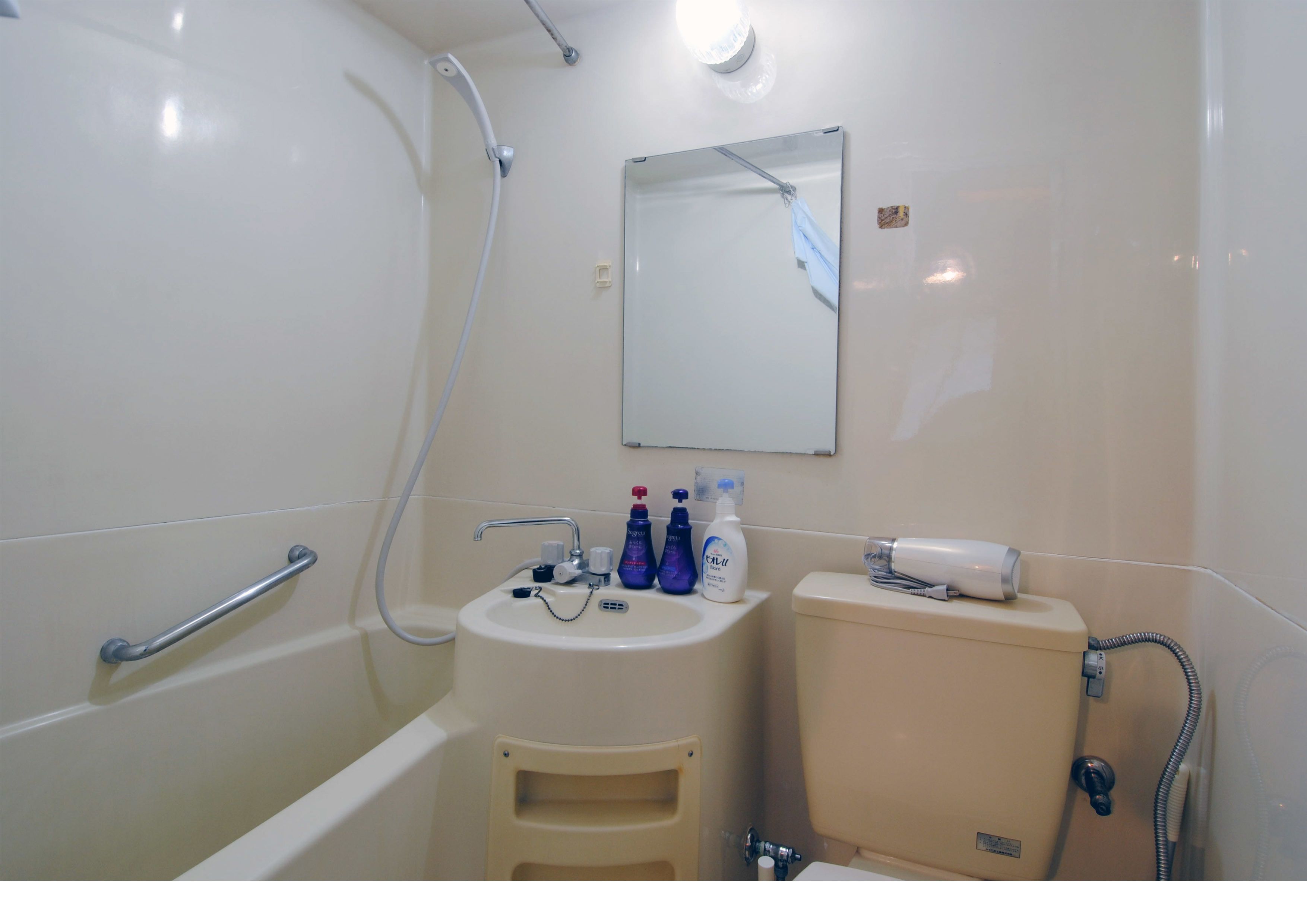 Kylpyhuoneessa on kylpyamme, pesuallas ja wc-istuin. Pesualtaalla on hygieniatuotteita ja wc-istuimen päällä hiustenkuivaaja.