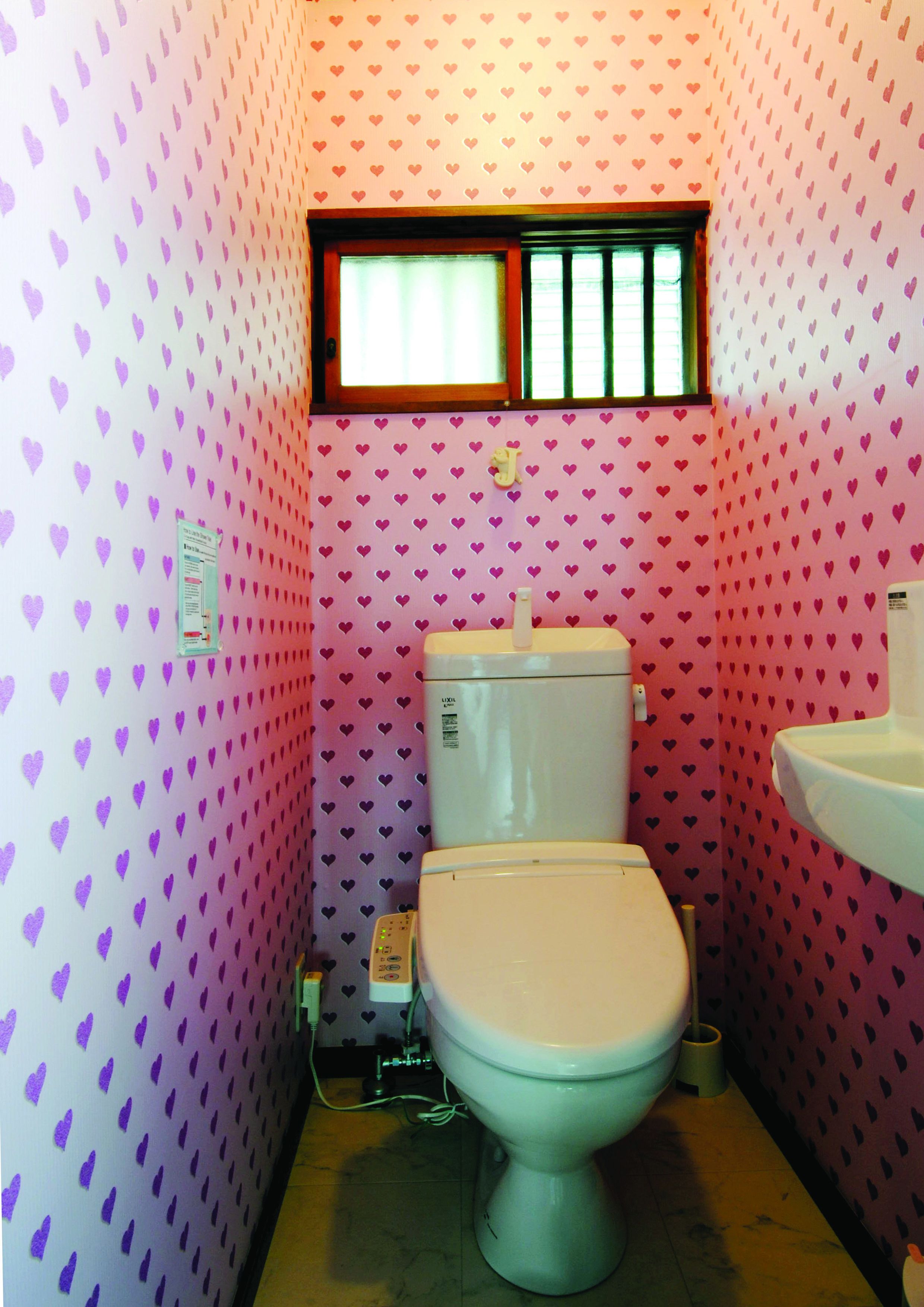Ein kleines Badezimmer mit Toilette, Waschbecken und Fenster.
