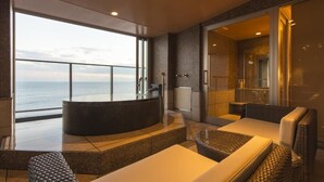 A modern, spacious balcony with a curved seating area, a built-in hot tub, and a view of the sea. - Inatoriso (Higashiizu)