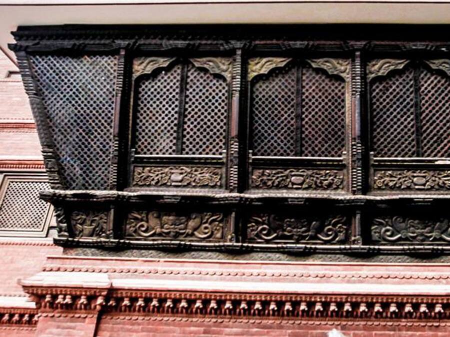 A detailed architectural facade with ornate carvings and a lattice window design.