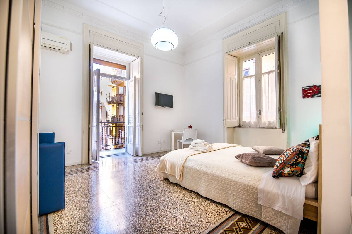 Une chambre à coucher avec un lit, une télévision et une fenêtre.