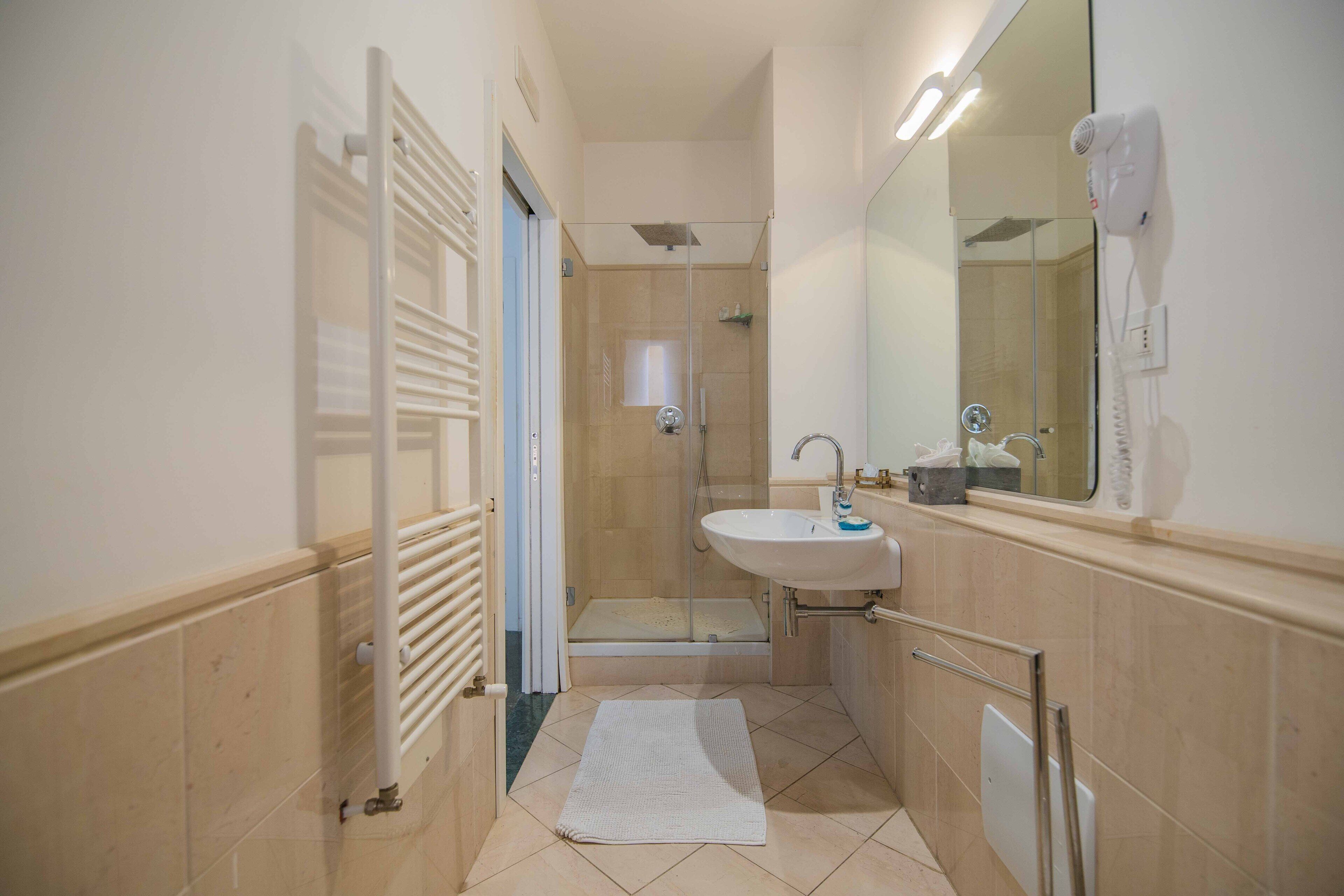 Une petite salle de bain avec une douche, un lavabo et un miroir.