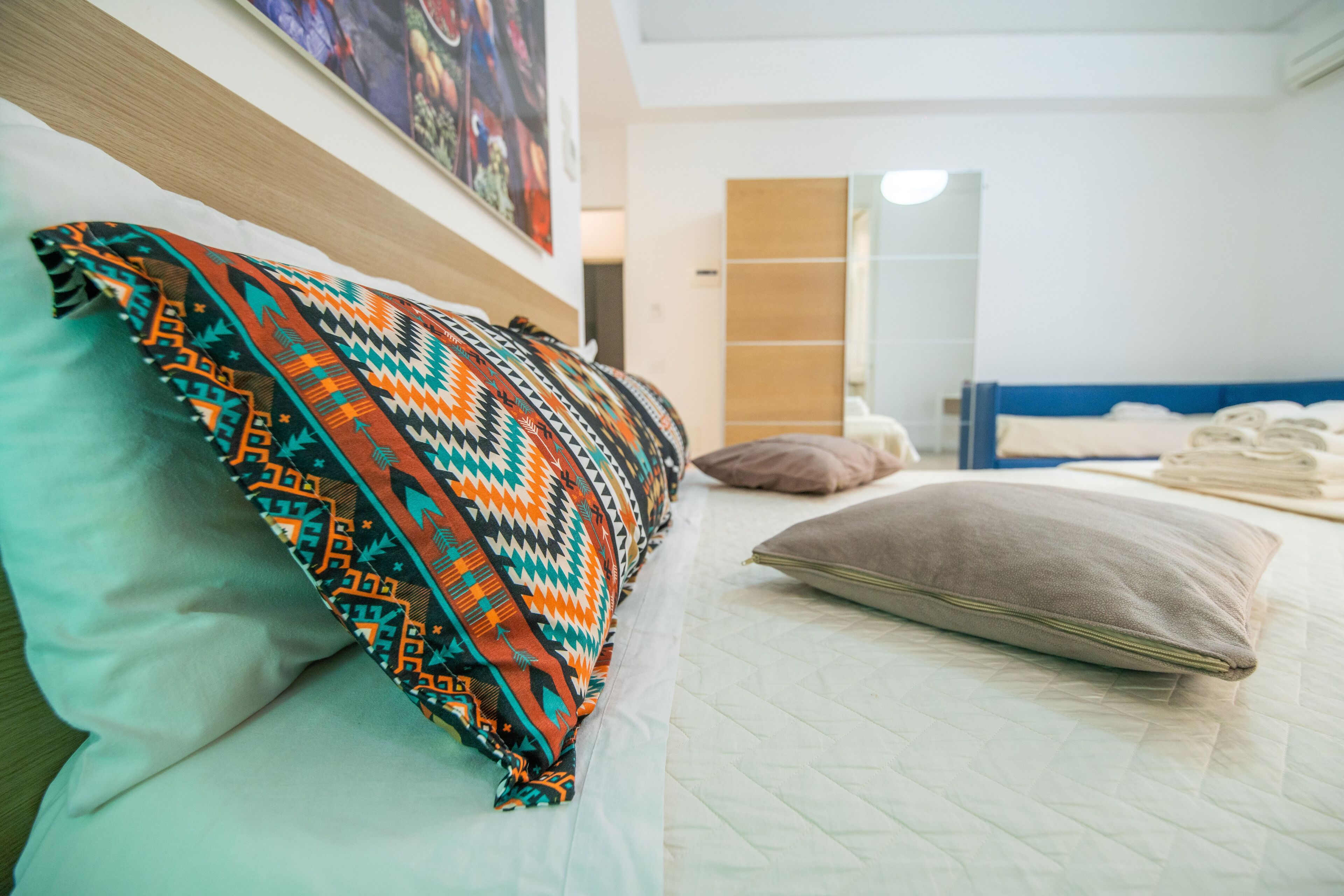 Una cama bien hecha con un edredón estampado, una almohada y una toalla doblada.