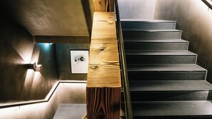 A staircase with a wooden handrail and a metal banister, leading to a landing with a framed picture. - Severins The Alpine Retreat (Lech am Arlberg)