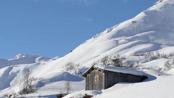 A wooden cabin in a snowy landscape with a clear blue sky.