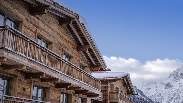A wooden chalet with balconies, large windows, and a mountain backdrop. - Severins The Alpine Retreat (Lech am Arlberg)