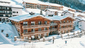 A wooden chalet-style hotel with balconies and a snow-covered landscape. - Severins The Alpine Retreat (Lech am Arlberg)