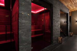 Un interior moderno con pared de piedra, iluminación roja, zona de baño de vapor y techo de madera.