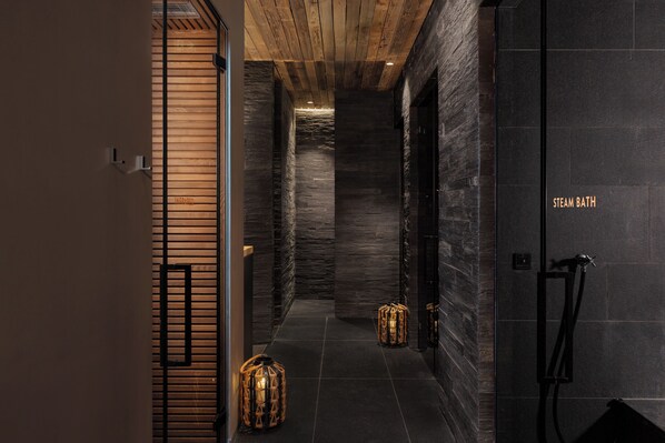 Un interior moderno con techo de madera, paredes de piedra y zona de baño de vapor.