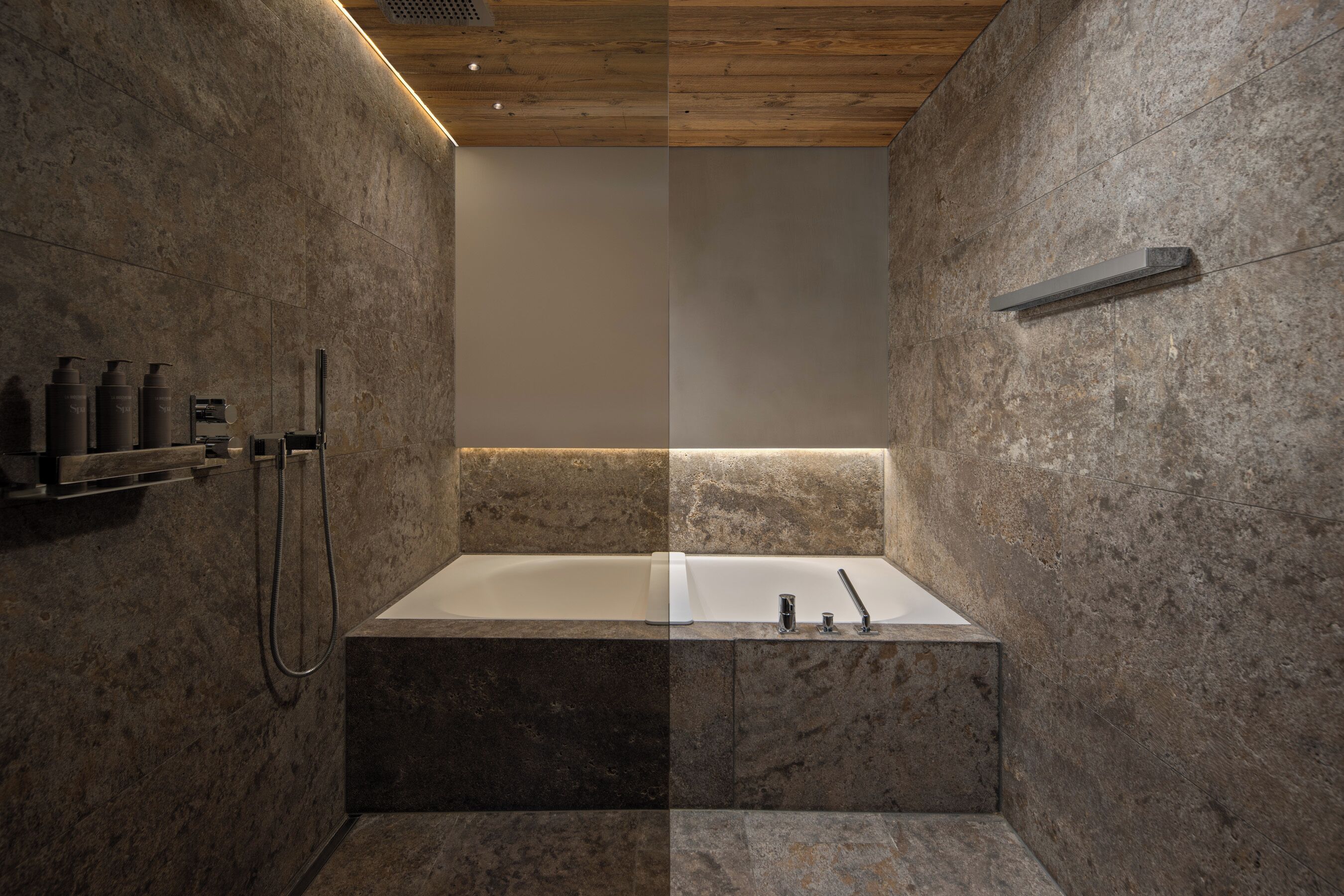 Ein modernes Badezimmer mit freistehender Badewanne, einer Duschkabine mit Handbrause und einem Ablagefach für Pflegeprodukte.