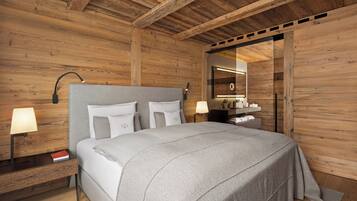 Een moderne slaapkamer met een houten plafond, een bed met witte beddengoed, nachtlampen en een spiegel met houten lijst.