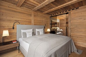 Un dormitorio moderno con techo de madera, una cama con ropa de cama blanca, lámparas de noche y un espejo con marco de madera.