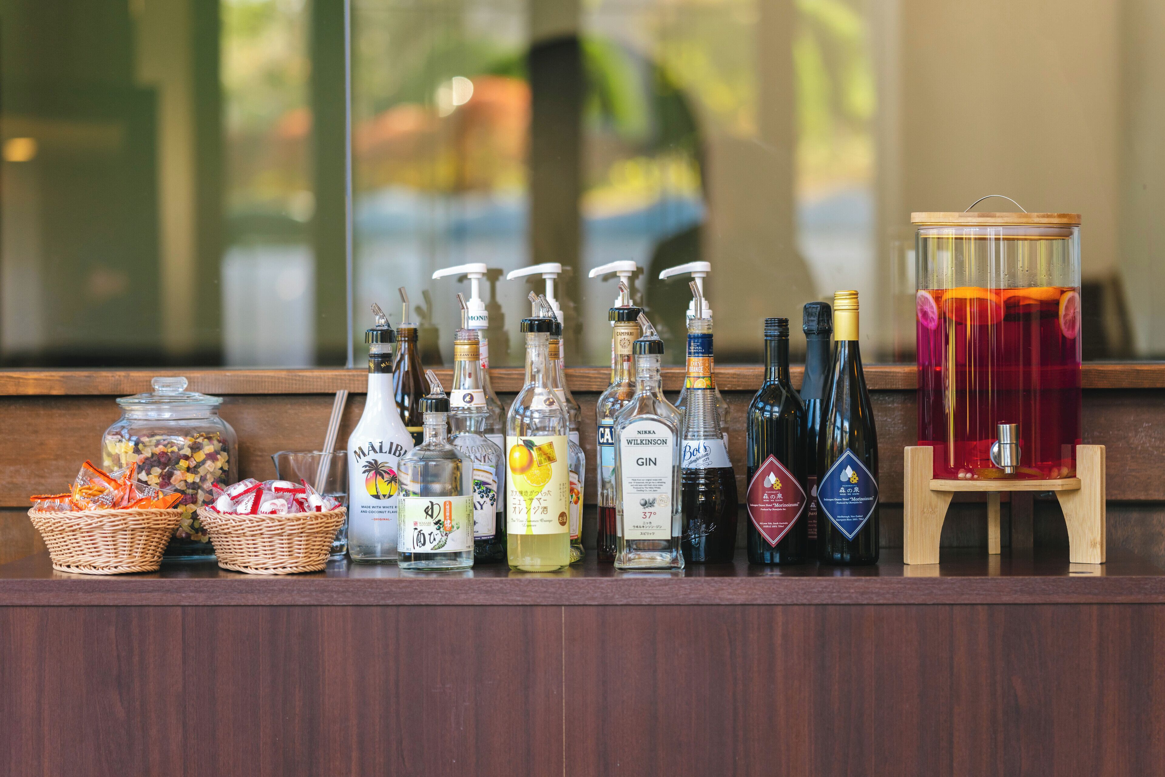 A bar area with various liquor bottles, a large jar of snacks, and a drink dispenser.