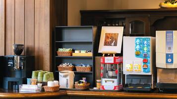 A coffee station with a coffee machine, a milk frother, and a display of coffee cups and a coffee grinder.