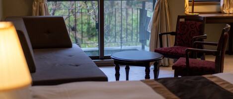 Una habitación de hotel con una cama, un ordenador portátil sobre la cama, una mesita redonda pequeña, una silla y una lámpara.