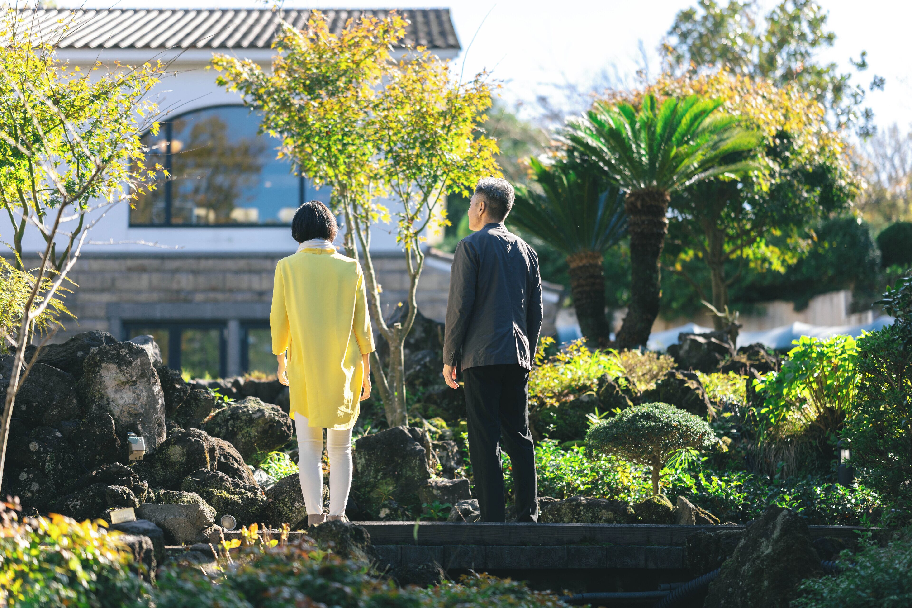 A couple standing in a garden with a traditional building in the background.