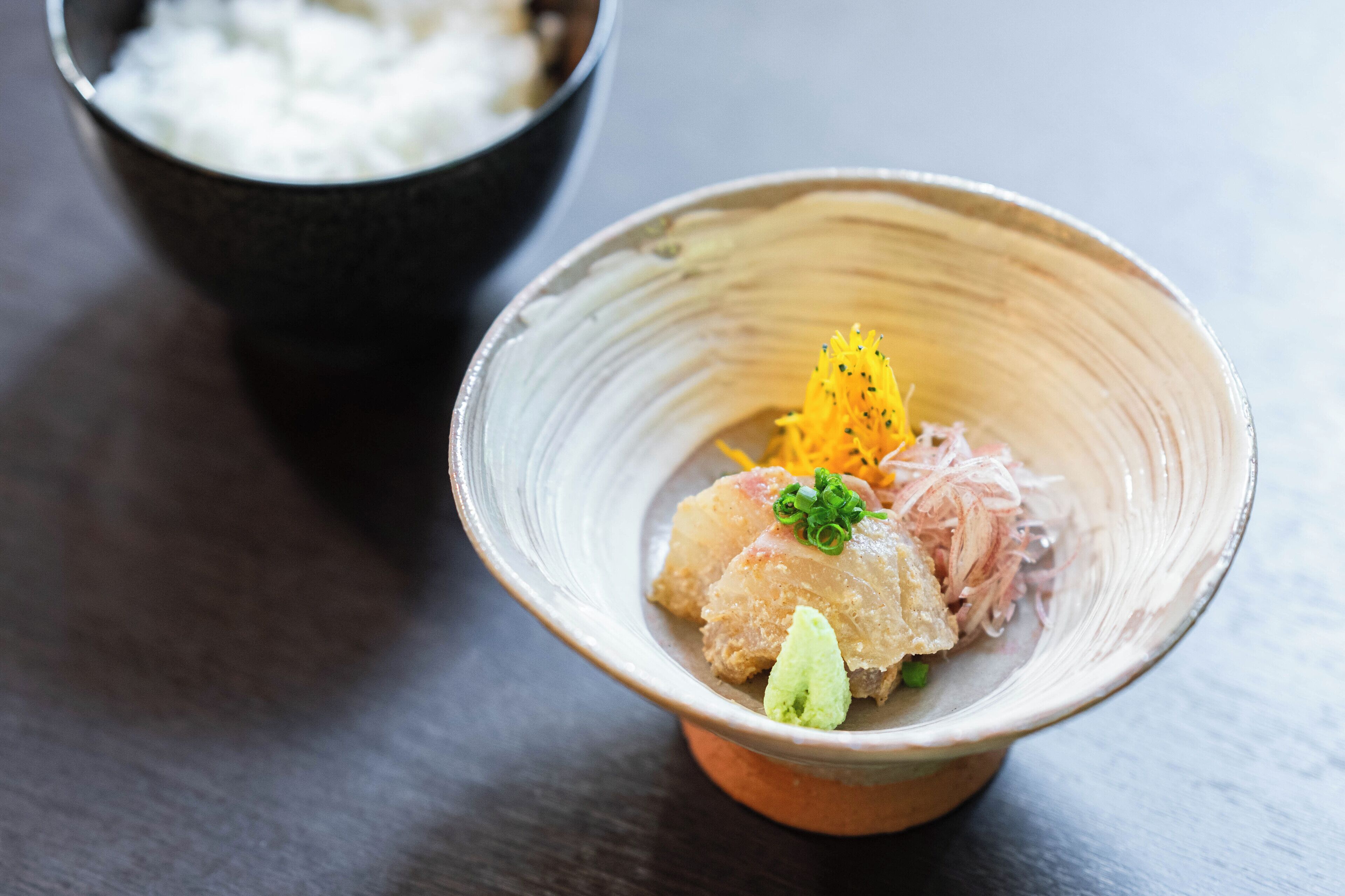 A bowl of sushi with a side of rice.