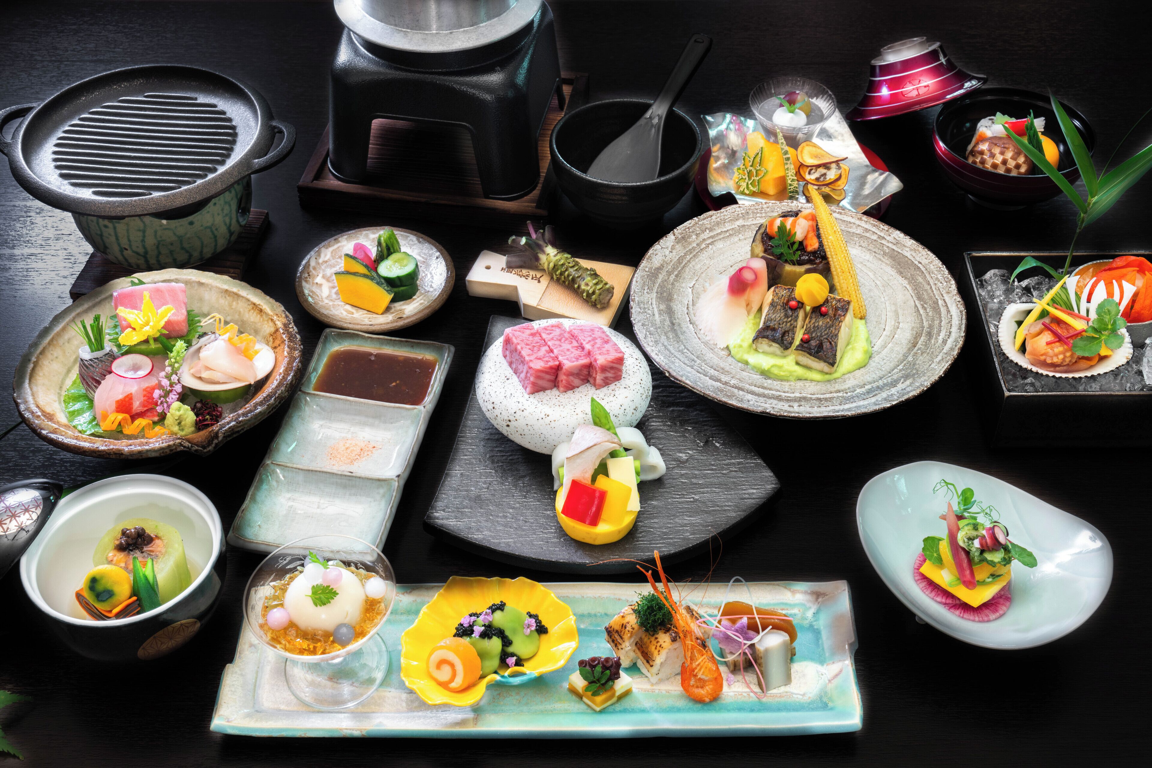 A variety of dishes on a table, including sushi, sashimi, and other Asian cuisine.