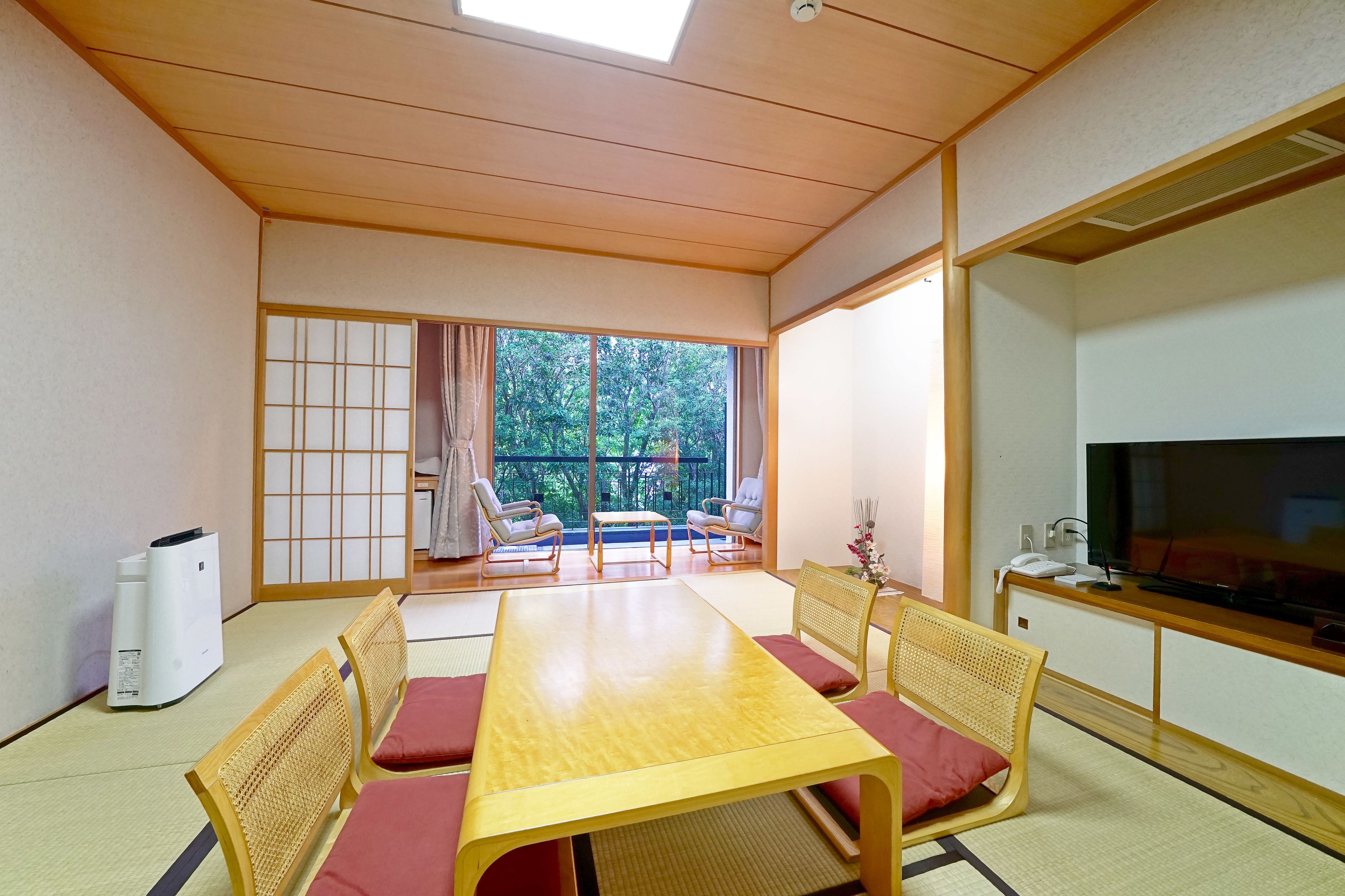 A traditional Japanese-style room with tatami flooring, a low wooden table, and a TV on a wooden stand.
