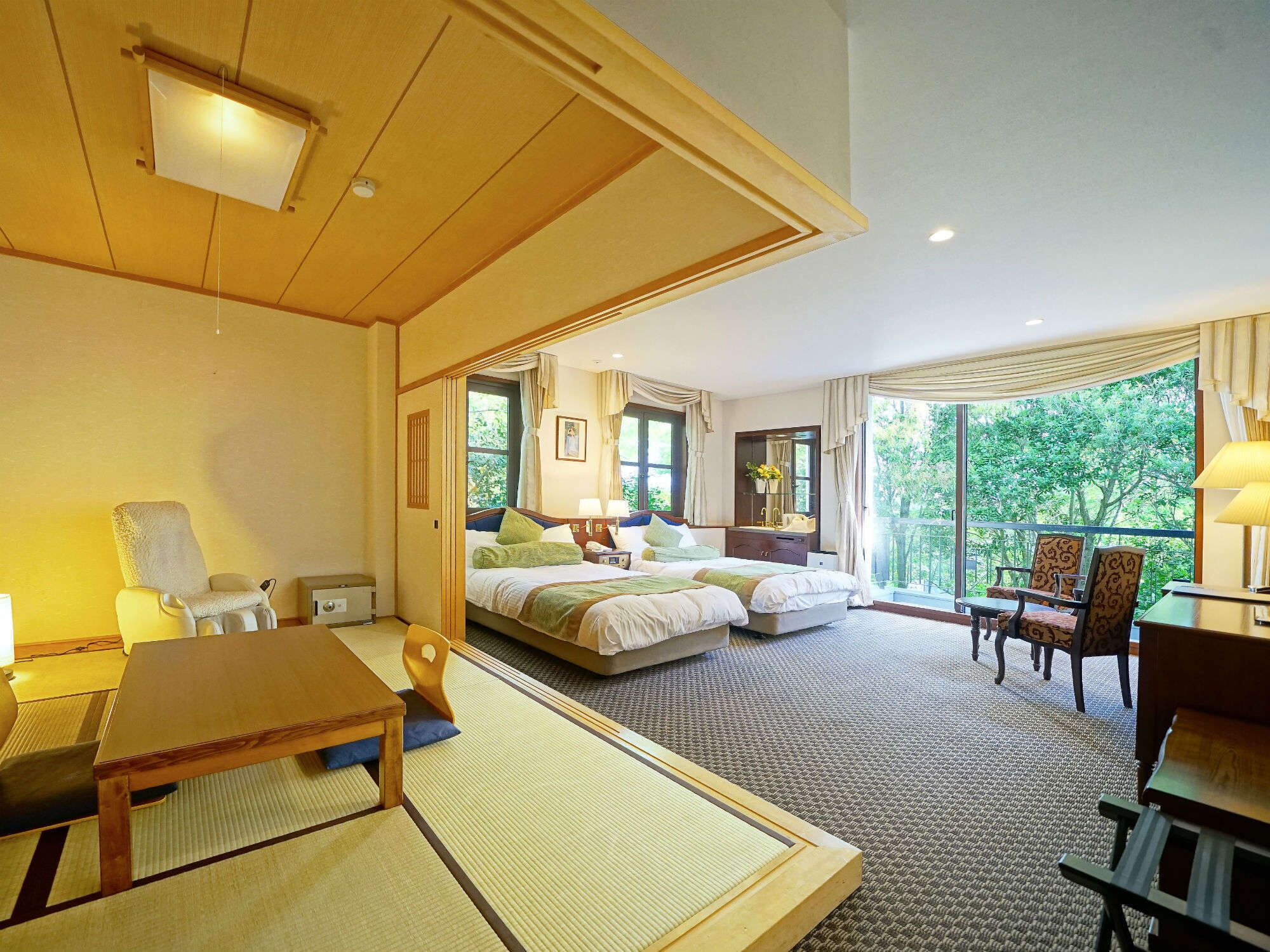A hotel room with a bed, a desk, a chair, and a view of greenery.